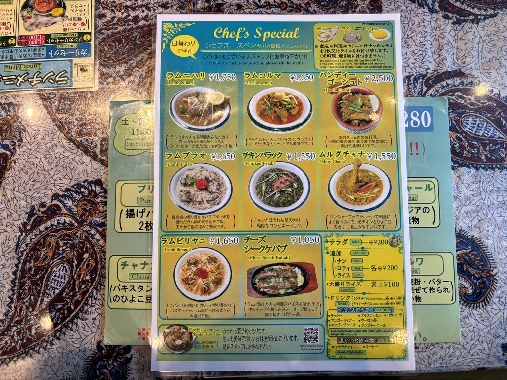 ナワブのカラー印刷ランチメニュー。カレーセット、ビリヤニ、ドリンク、デザート、タンドール料理が写真付きで紹介されている。