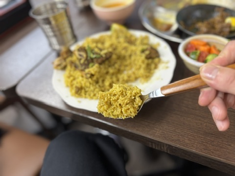 黄色く色づいたご飯と骨付きビーフを混ぜながら食べるシーン。スパイスとマスタードオイルが香るバングラデシュ式ごちそうご飯。