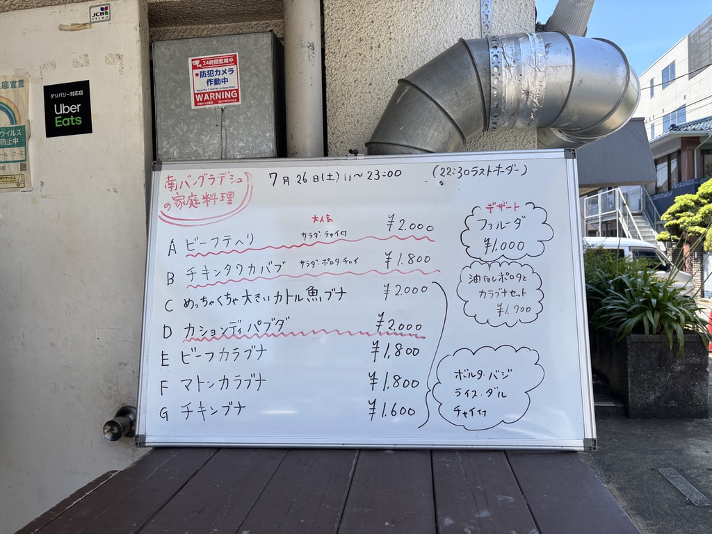 「サルシーナハラールフーズ店頭の手書きホワイトボードメニュー。ビーフテハリやカラブナなど日替わりバングラデシュ家庭料理。」