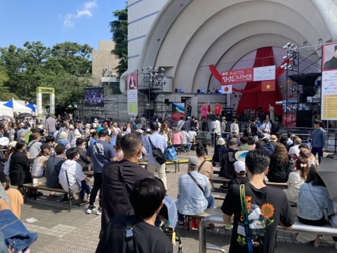 代々木公園イベント広場で行われたベトナムフェスティバル、屋外ステージ前に集まる多くの観客たち。赤いステージ装飾にはベトナム国旗とイベントバナーが掲げられている。