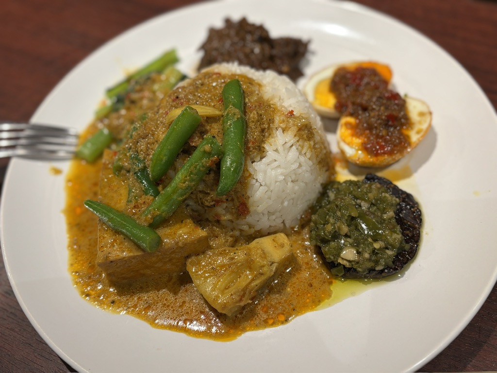 「スマトラスタイルのインドネシア料理ナシパダン。野菜カレー、ルンダン、青唐辛子ソースなどが盛られたプレート」