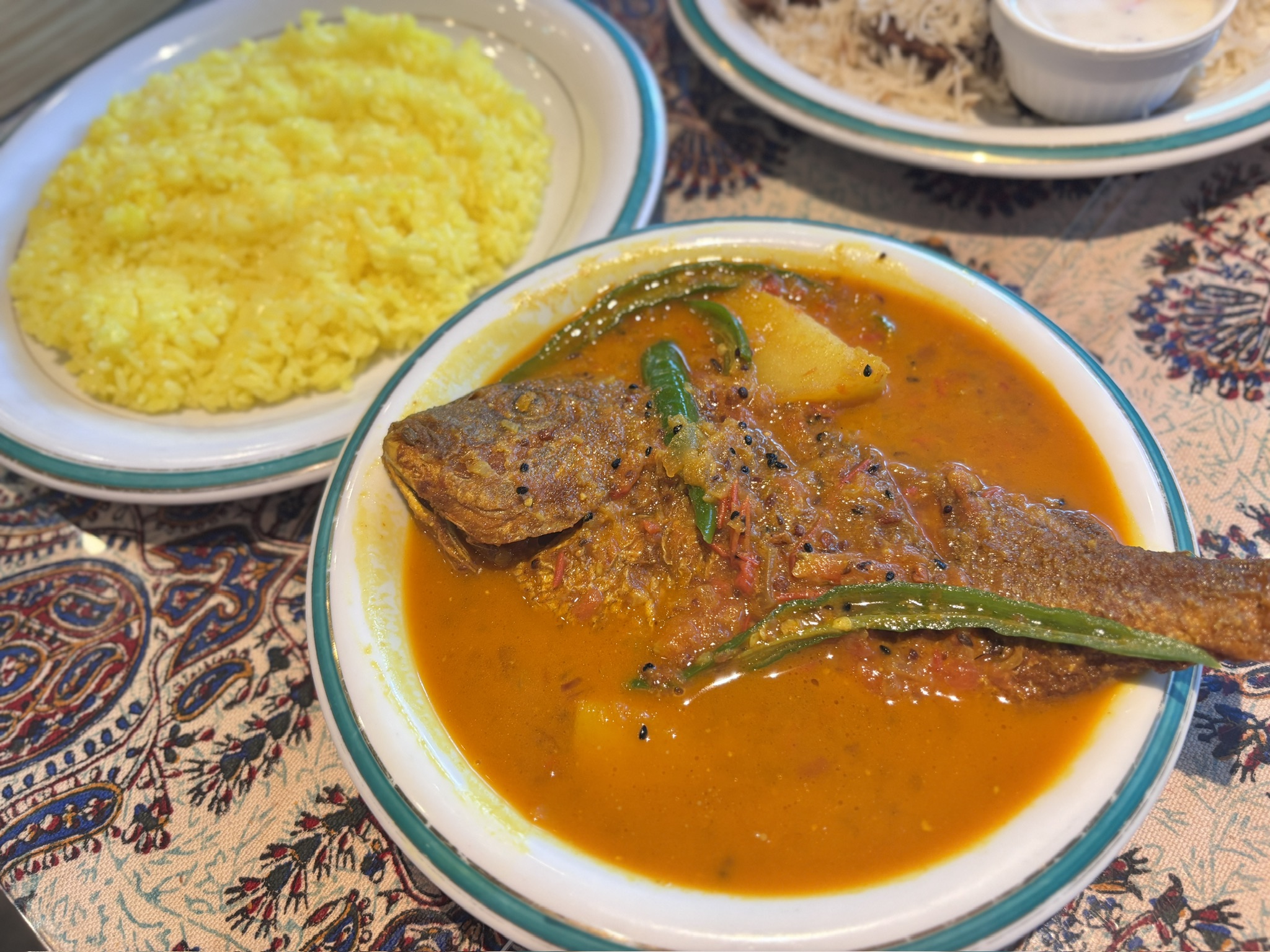 さらりとしたスープ仕立てのフィッシュカレー。スパイスの香るターメリックライスと一緒に提供されるコルカタ風スタイル