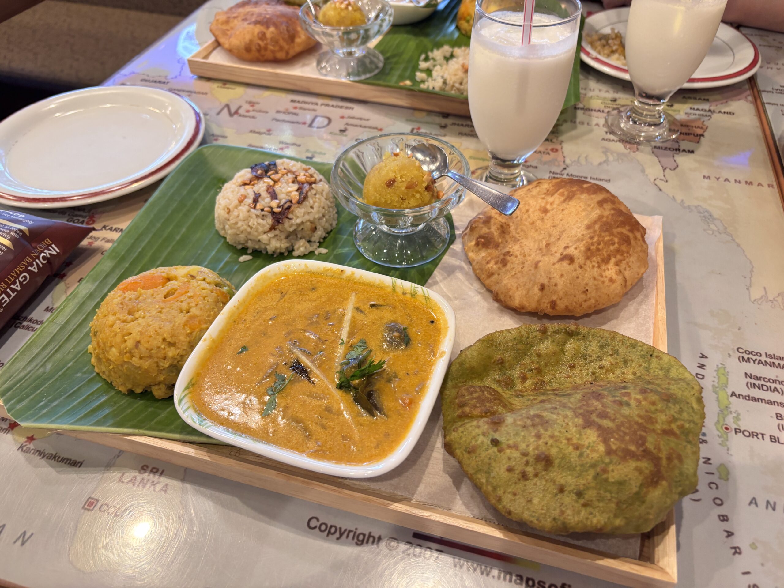 ケララバワンのスペシャル南インドプレート。バナナリーフにのせたカレー、プーリ、デザート、ラッシーが美しく並ぶ