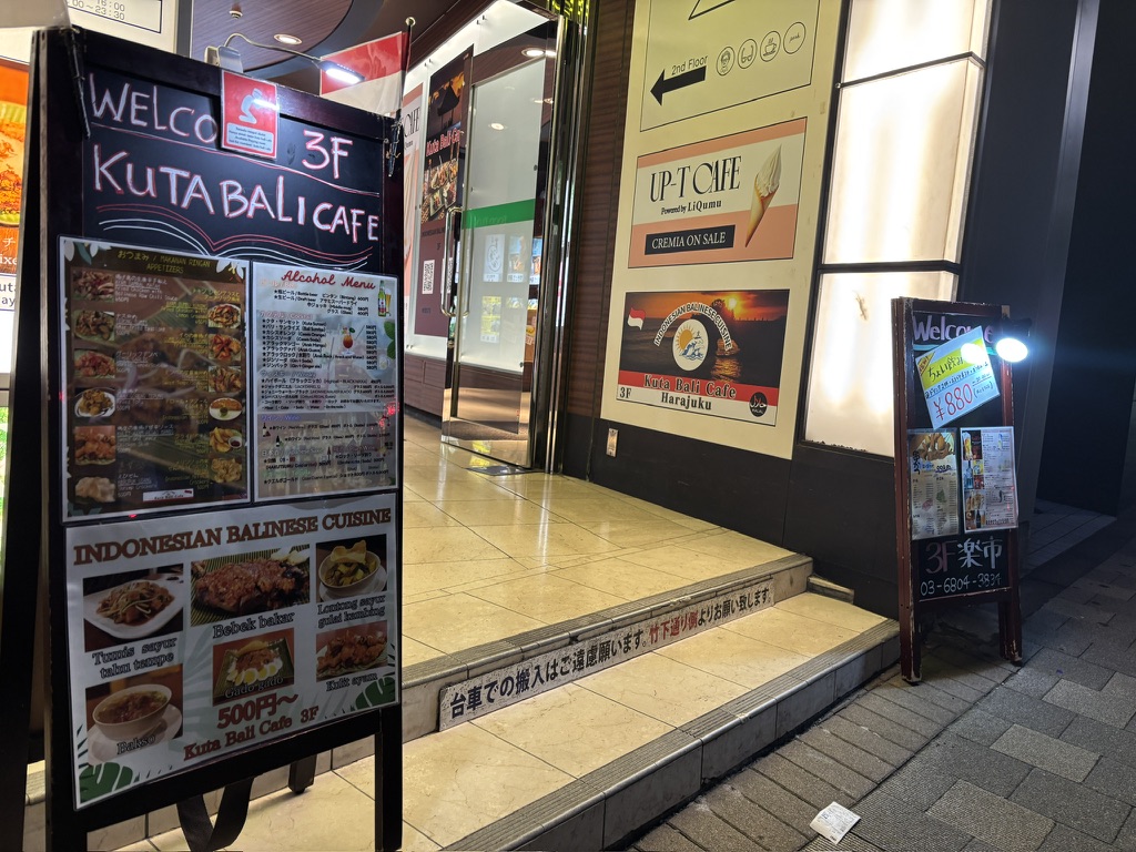 　「『Kuta Bali Cafe』店内の大型看板。バリの夕景と料理写真が映る雰囲気ある装飾」