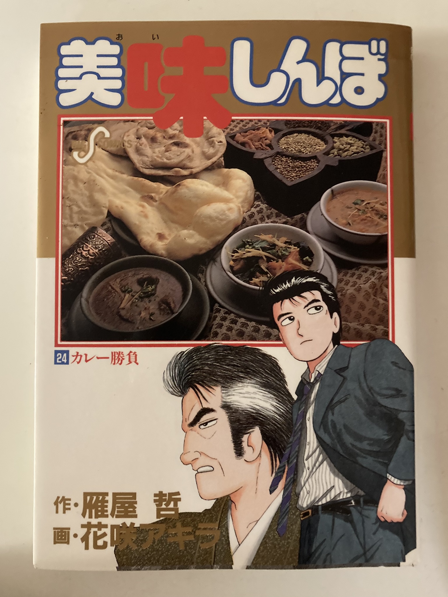 美味しんぼ」第24巻の表紙。特集は“カレー勝負”。表紙にはナンと数種のカレーが並び、主人公・山岡士郎と海原雄山の姿も。チャットマサラが登場する伝説的エピソード。