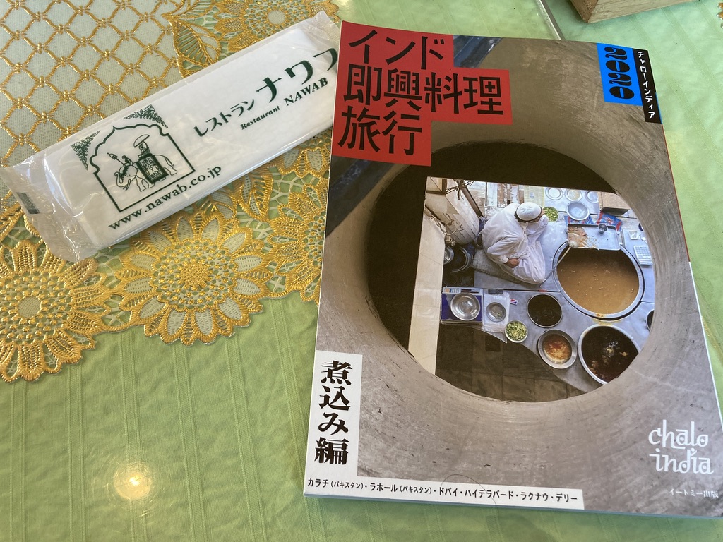 パキスタン・ラホールの煮込み料理特集『インド即興料理旅行』の本と、ナワブのロゴ入りおしぼりが並ぶテーブル　＠旧ナワブ