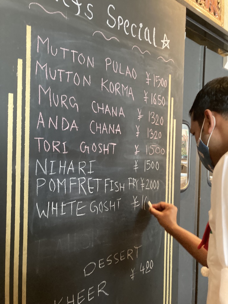 ナワブ新宿の黒板に書かれたスペシャルメニュー。マトンプラオやホワイトゴーシュトなどの料理名と価格が並ぶ。
