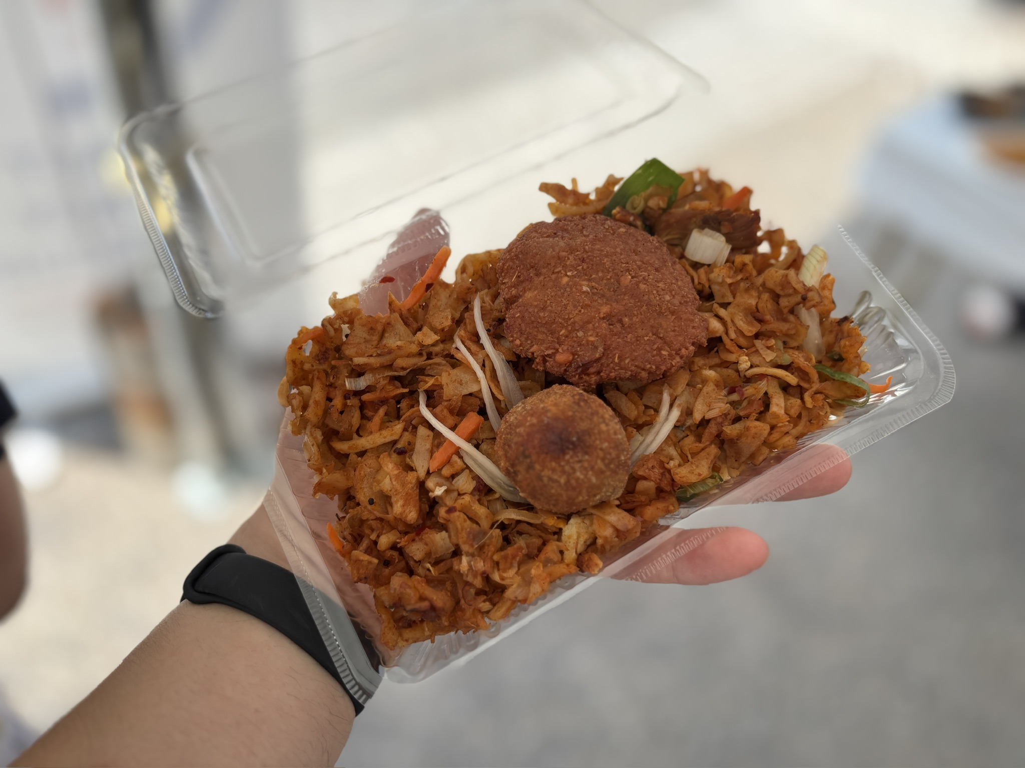 透明パックに盛られたコットゥロティ。細かく刻んだロティと野菜の上に、マサラワデとカトゥレッツがのっている。