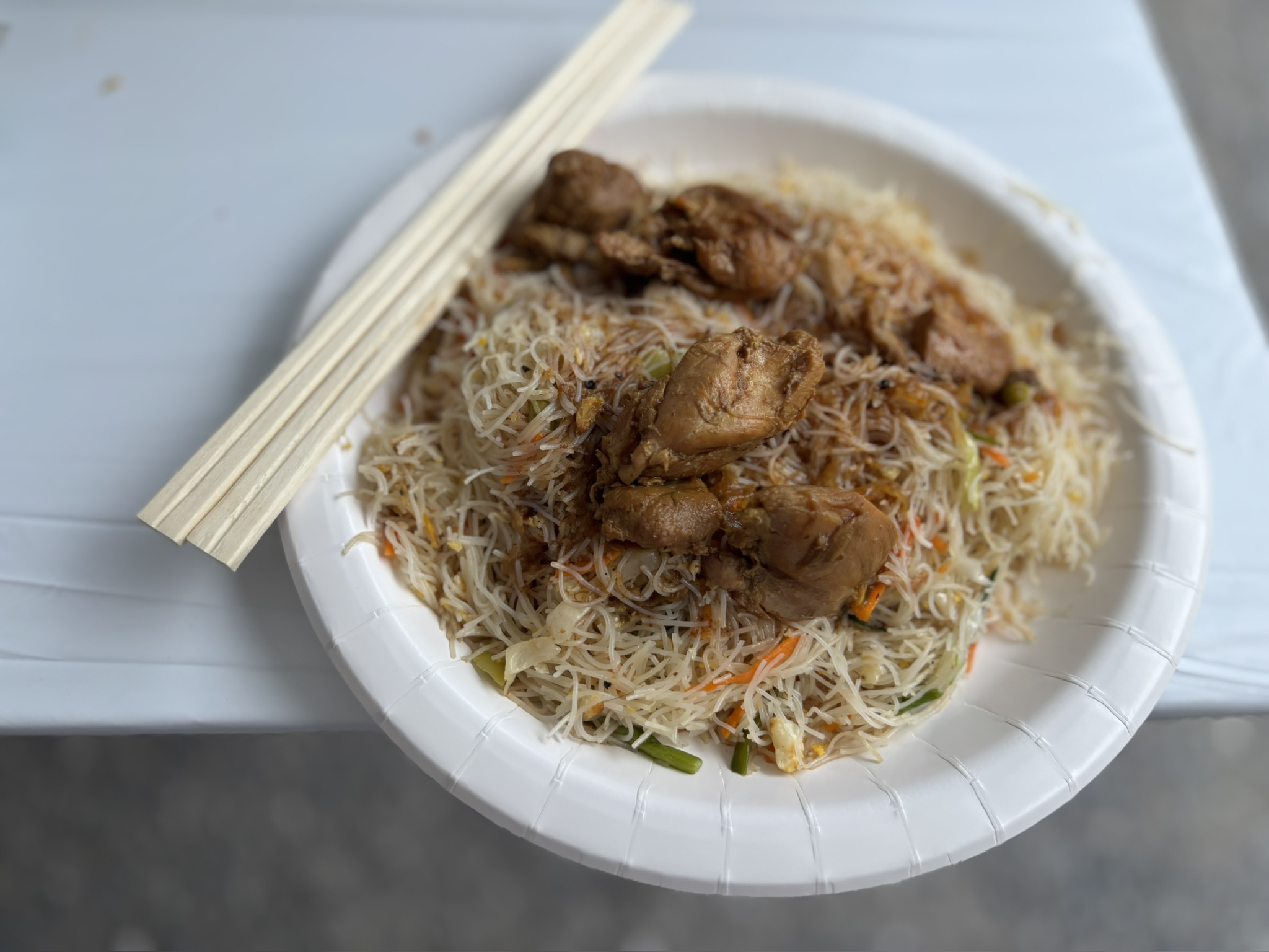 紙皿に盛られたインディアッパーに、フライドチキンとカレーがかかっている。