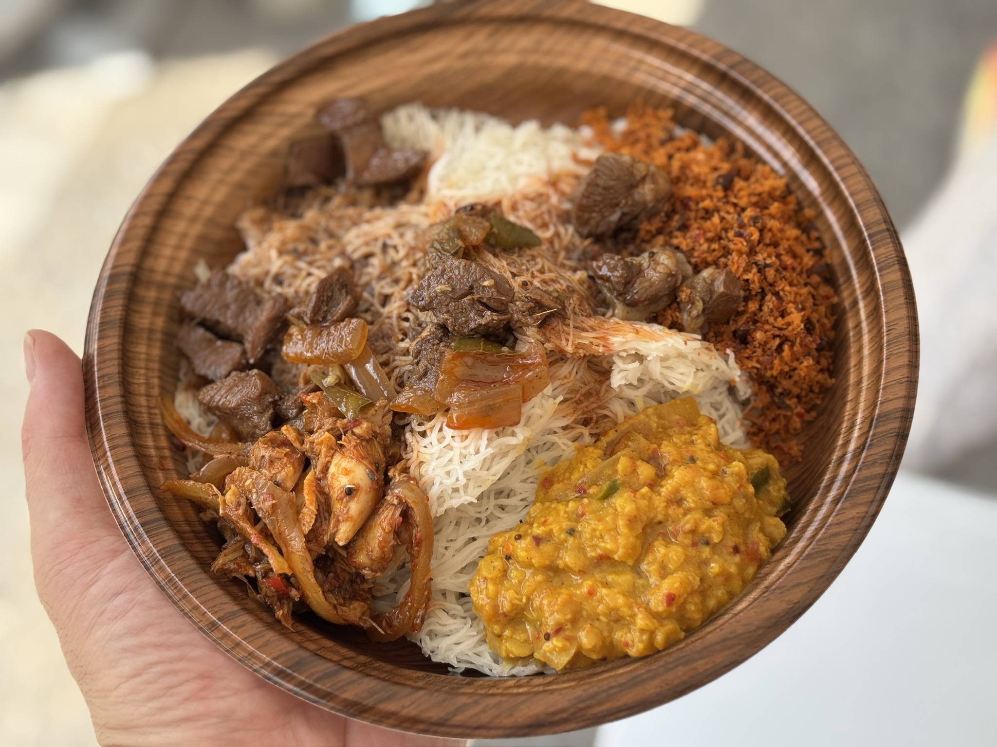 木目調の器に盛られたインディーアッパー。マトンカレー、レンズ豆カレー、ポルサンボルが彩りよく添えられている。