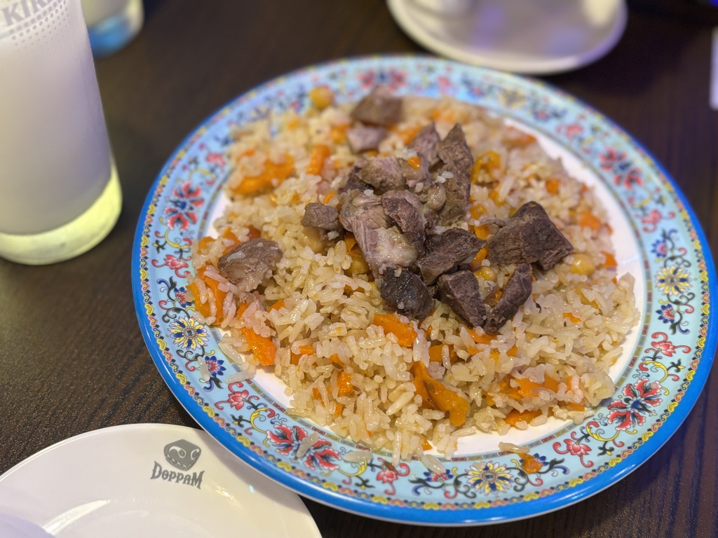  ウズベキスタン風ピラフ「ポロ」。しっとり米と甘く煮込まれたにんじん、骨付きラムの豪快なトッピングが映える一皿