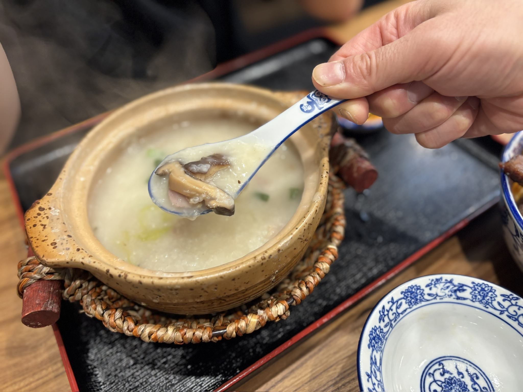 牛雑煲（780円）。赤土鍋に牛モツ煮込み。トレイに落花生の小鉢と王老吉。