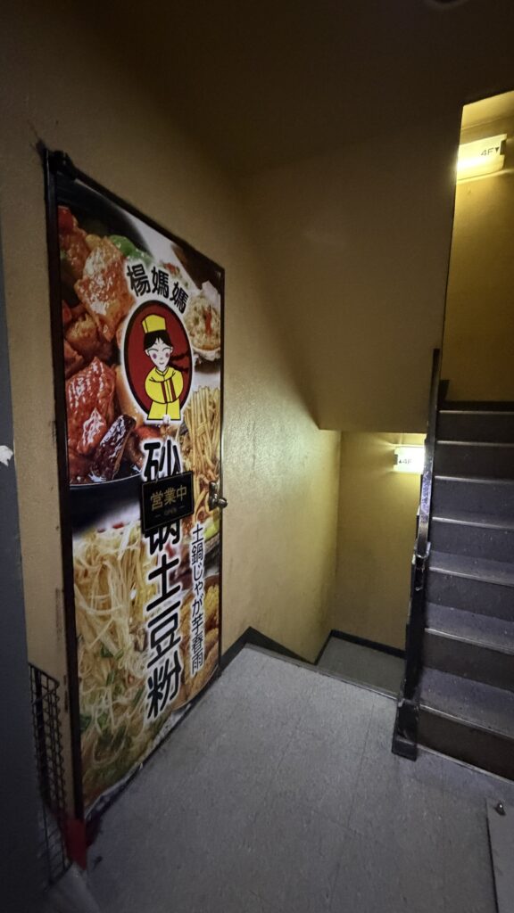 雑居ビルの階段と杨妈妈の入口ポスター(営業中)