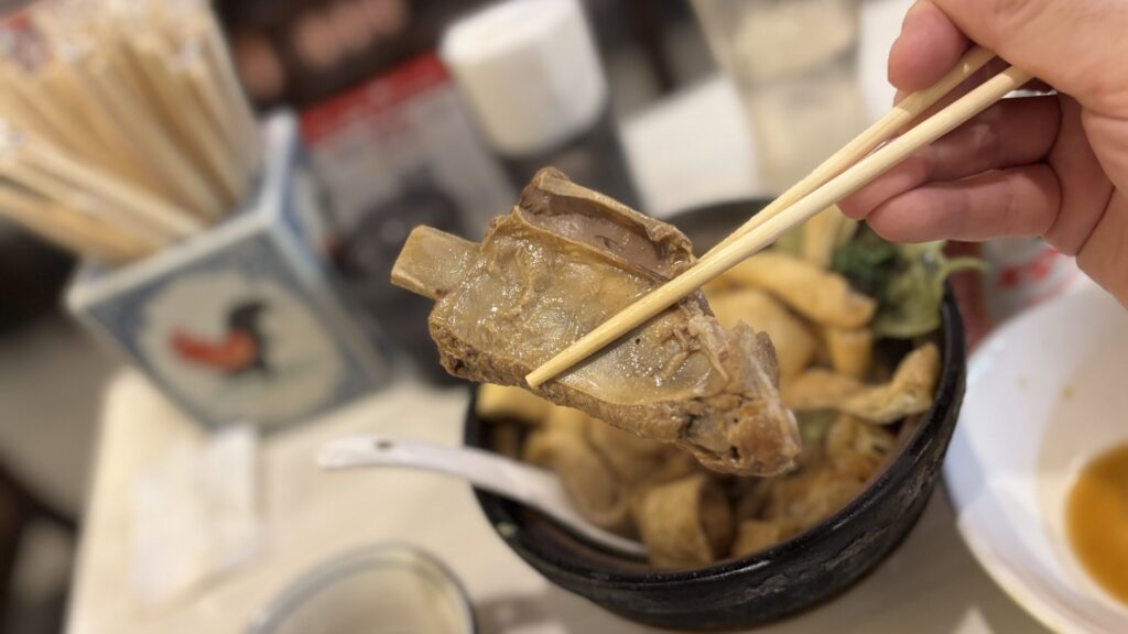 箸で取り上げた魚肉骨茶の骨付き肉
